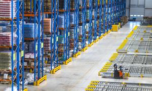 High-density warehouse with numbered racking aisles, palletized FMCG goods, and electric pallet truck — illustrating structured inventory management in distribution operations.
